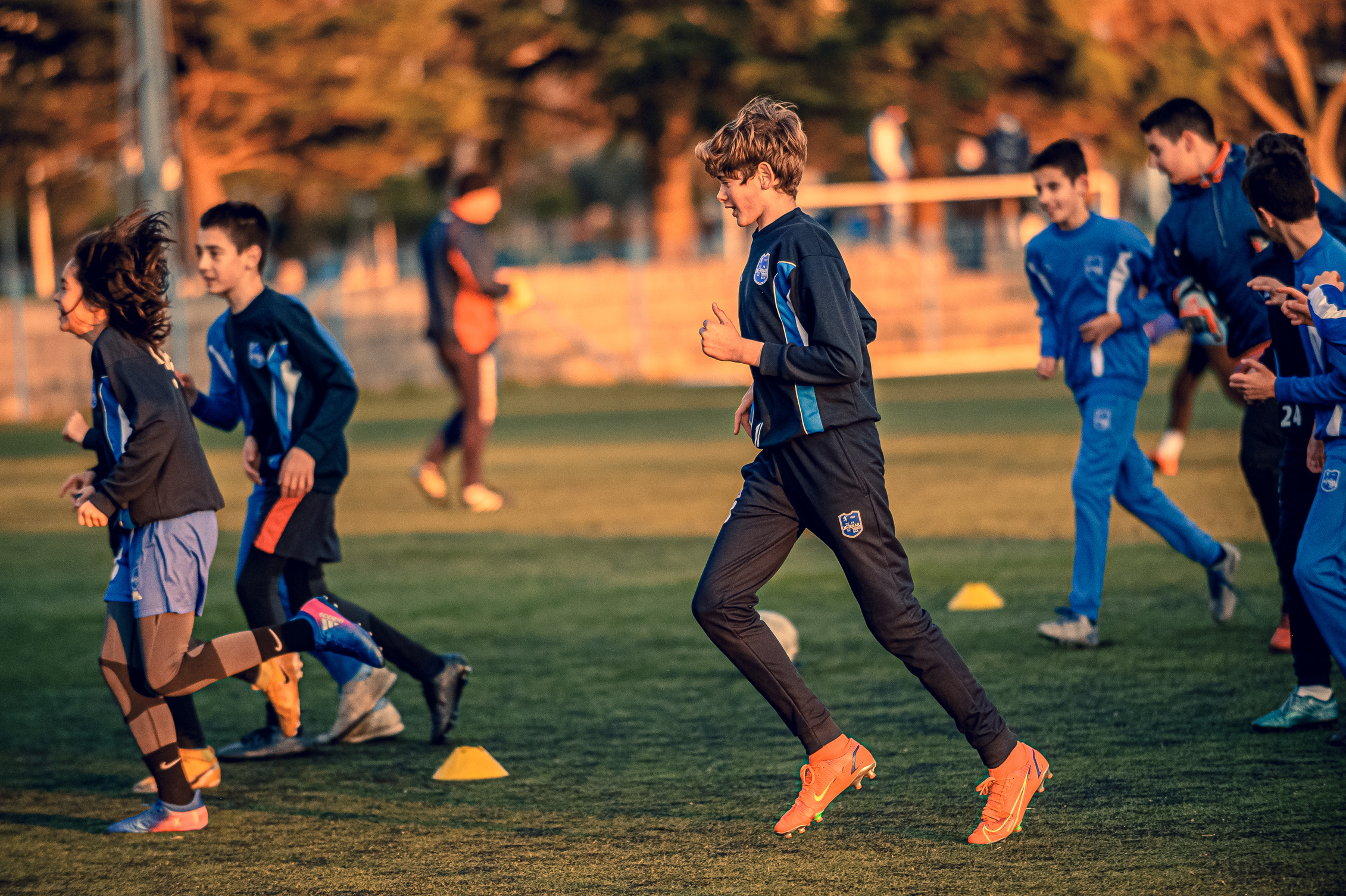 Boys in Blue Uniforms Running on a Football Field